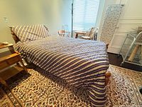 Full view of assembled maple twin bed with striped bedding, showing headboard, footboard, side rails and mattress