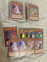 Stacked Yu-Gi-Oh! cards in sleeves showing Ghost Reaper & Winter Cherries and other foils