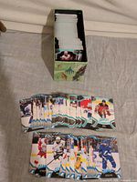 Open storage box filled with stacked hockey cards; several cards laid out face-up