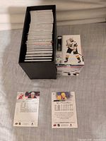 Black storage box filled with stacked hockey trading cards, two sample cards displayed