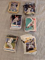 Five visible stacks of assorted baseball cards on fabric surface