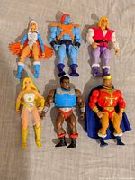 Group shot of all six Masters of the Universe figures standing on fabric backdrop