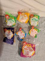 Group shot of all seven sealed Happy Meal toys in assorted bags