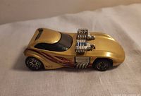 Side profile of gold Hot Wheels Twin Mill showing body color, twin engines, flame graphics