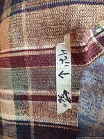 Close-up of fabric showing plaid weave and tape indicating 42 x 36 inches