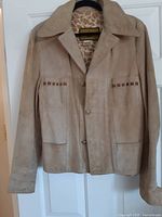 Front view of tan suede leather jacket showcasing pockets, buttons and collar