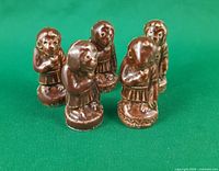 Five Wade brown glazed monkey figurines standing upright on green background