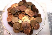 Top view of loose pennies on dish showing obverse and reverse designs