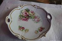 Full view of Bavarian porcelain plate with handles, gilt edge, floral motif and hanging clips