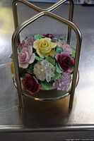 Full view of Capodimonte porcelain flower arrangement within metal stand