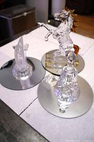 Group shot of glass horse, tower and bell on mirrored bases