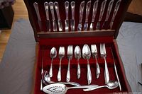 Open flatware chest showing Rogers IS and Rogers Oneida Lilac pattern silverplate utensils including knives, forks, spoons and serving pieces