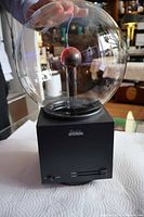 Front view of plasma ball lamp with hand touching globe showing size and base details