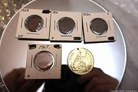 Group of five coins in flips on reflective surface