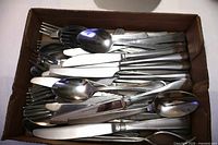 Box of mixed stainless steel cutlery showing quantity and variety of patterns