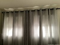 Four gray-silver curtain panels hung on rod