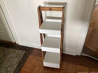 Full view of vertical three-tier shelf showing white trays and natural wood frame