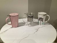 Front view of three mugs with lids