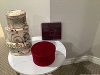 Group view of three patterned hat boxes, red velvet box, and burgundy jewelry tray