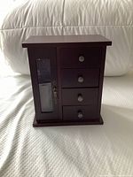 Front view of closed jewelry box showing glass door and three drawers