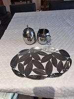 creamer, sugar bowl and leaf trivet on table