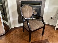 Front view of wooden side chair showing striped seat and back, armrests and tapered legs