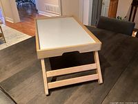 Light natural wood tray standing with legs extended on table