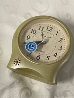 Front view of gold-tone quartz alarm clock showing dial and hands