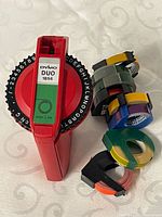 Red Dymo Duo 1856 label maker alongside stack of tape rolls