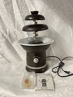 Front view of fountain with tiers, auger, dial, power cord, manual and toothpicks visible