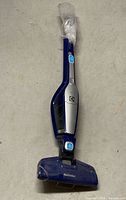 Full view of blue Electrolux cordless stick vacuum with adapter wrapped at handle