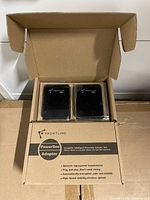 Open box showing two wrapped black Frontline adapters