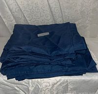 Stack of folded dark blue tablecloths on light patterned backdrop