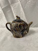 Front view showing elephant form, trunk spout, monkey on lid