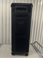 Front view of black wheeled duffel standing upright showing telescopic handle and logo patch