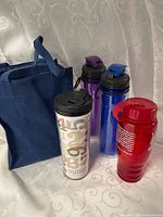 Group view of lunch tote, Starbucks travel mug, blue, purple, red water bottles