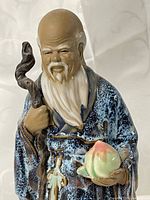 Close-up of statue upper body showing head, staff and peach