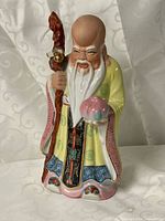 Front view of glazed Shou Xing statue holding peach and staff