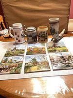 Group shot of two beer steins, drinking horn on stand, and six decorative tiles