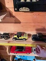 Row of first three vintage cars with tape measure