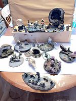 Group shot of entire assortment of pewter dioramas displayed on table and riser