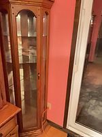 Full view of oak corner curio cabinet beside door
