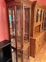 Full view of oak curio cabinet showing glass panels and interior shelves
