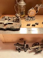 Group view of fighter jet, locomotive, stein, CIBC clock, micro cannons, cast cannons