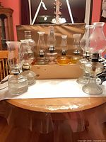 Group shot of nine glass oil lamps of varying heights on table