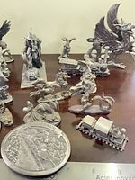 Overview of multiple pewter figurines including dragons, wizard, SOO TRAIN medallion, locomotive
