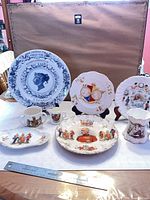 Group shot of all commemorative plates, bowl, mug, creamer and dish