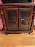 Front view of dark wood curio cabinet with glass doors