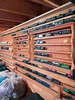 Wooden wall display filled with numerous metal model train locomotives and cars