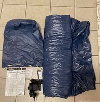 Deflated blue vinyl air mattress rolled with pump, instructions, accessories visible